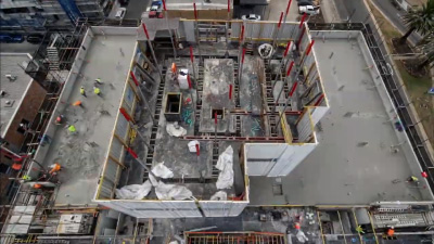 Workers pouring a large concrete slab during the day.