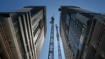 Two high-rise towers under construction with a tower crane between them